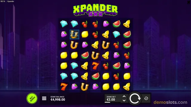 A slot game screen showing a 7x7 grid of fruit and object symbols with a '2x' multiplier highlight and a purple city skyline background.