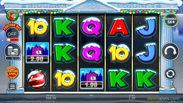 A snowy-themed slot game shows a 5x3 reel grid with symbols including K, Q, A, J, 10, a wrapped gift with a price tag, and a red ornament, with a balance of 998.00 and stake of 1.00.
